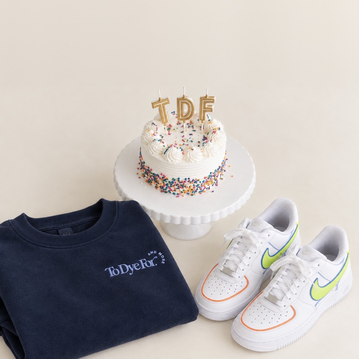 A navy To Dye For and More sweatshirt, a TDF birthday cake, and custom-painted sneakers