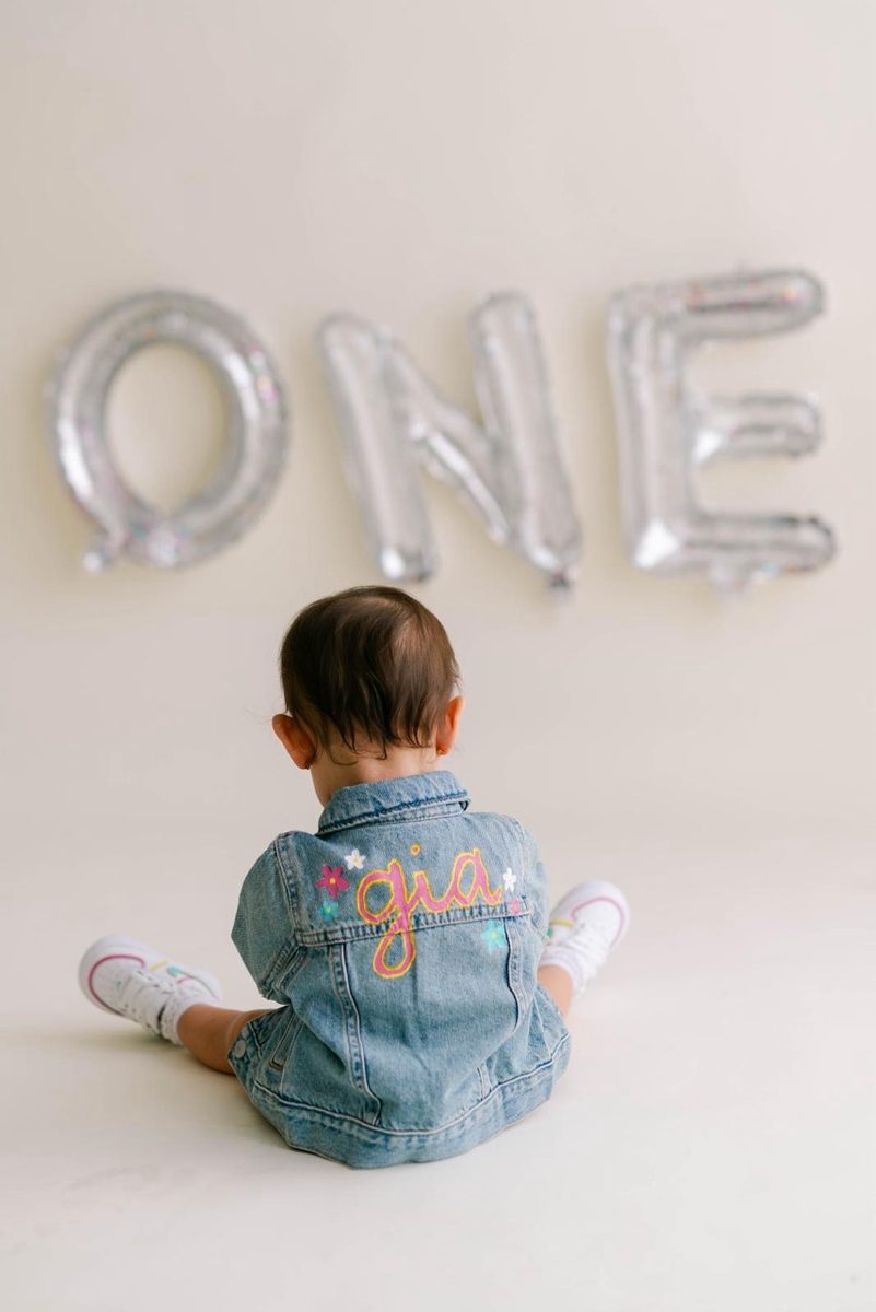 Baby in a hand-painted “Gia” jean jacket at her first birthday